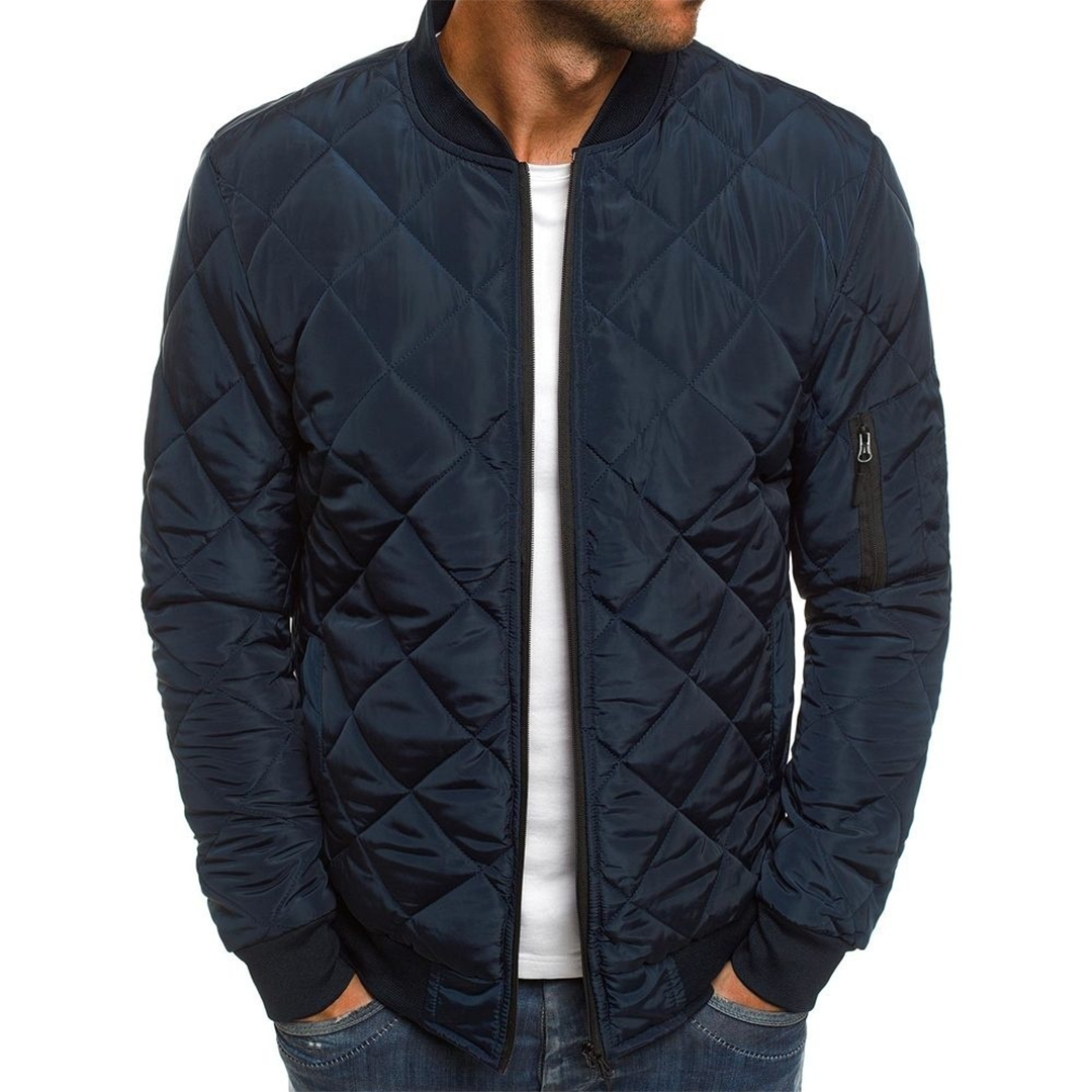 A man wearing a blue quilted men's bomber jacket with a round neckline and zip front.